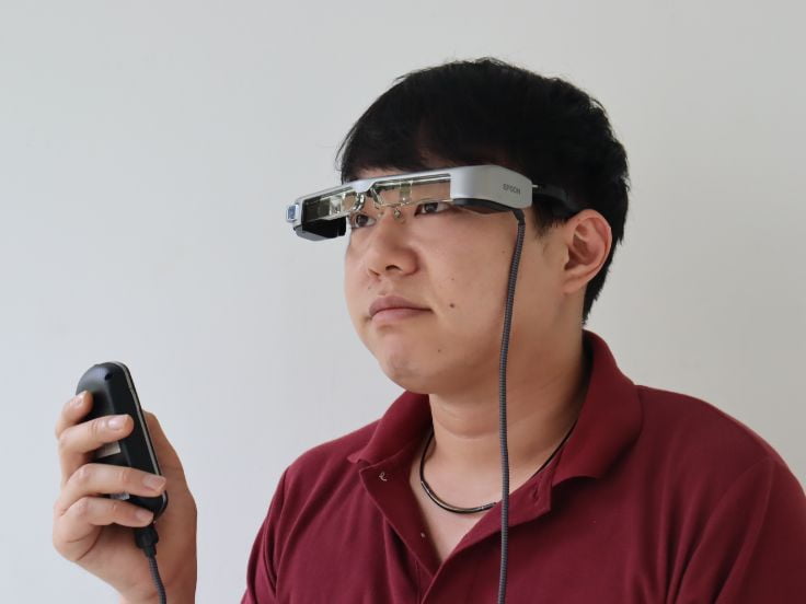 写真:メガネ型端末で聴覚障害者用字幕を使用する男性