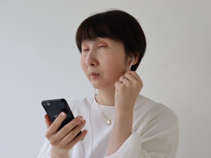 写真:バリアフリー音声ガイドを使用する女性